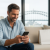 Confident man in Sydney apartment checking phone after discreet online purchase — harbour bridge view